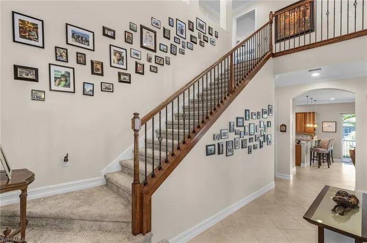 Staircase featuring arched walkways, tile patterned flooring, crown molding, and a towering ceiling