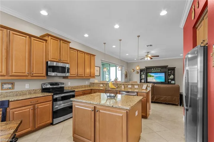 Kitchen featuring stainless steel appliances, a peninsula, ceiling fan, light tile patterned flooring, and open floor plan