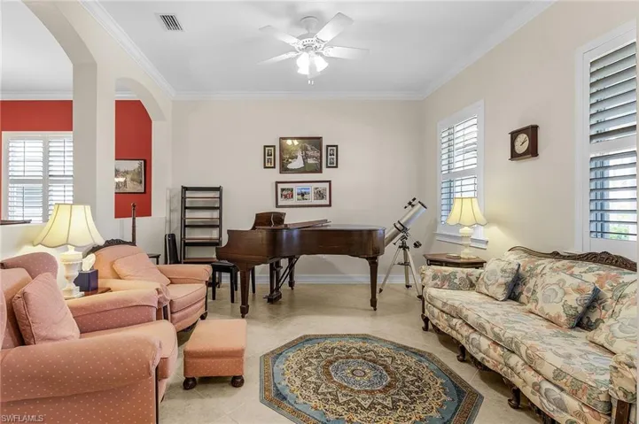 Living room featuring crown molding, a ceiling fan, healthy amount of natural light, and arched walkways