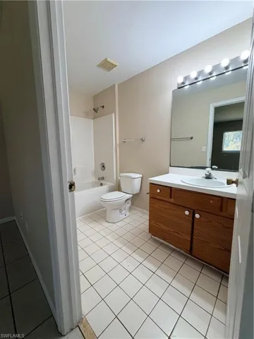 Full bath featuring vanity, light tile patterned floors, and shower / tub combination