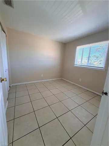 Unfurnished room with light tile patterned flooring and baseboards