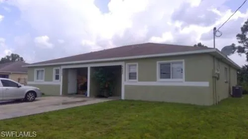 View of front facade with stucco siding, a front yard, and concrete driveway