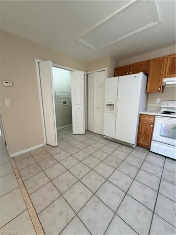 Kitchen with wood finish cabinetry, stove, refrigerator, light countertops, and exhaust hood