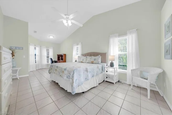 Bedroom with light tile patterned flooring, a ceiling fan, and high vaulted ceiling