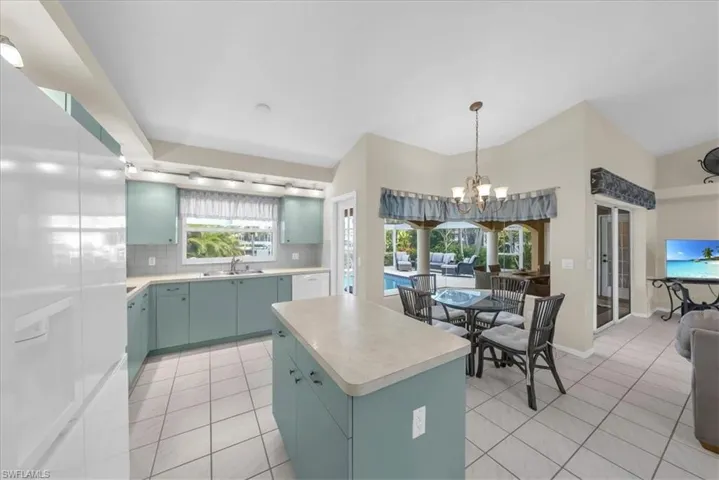 Kitchen featuring white appliances, decorative backsplash, light countertops, a center island, and light tile patterned floors