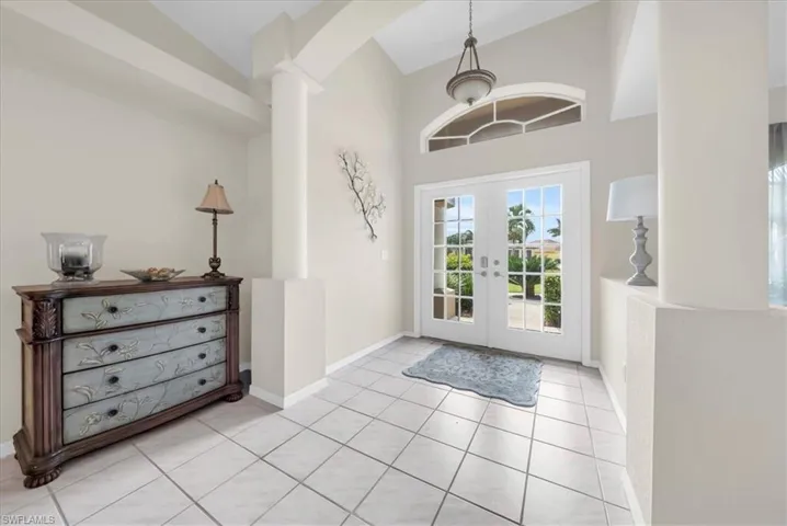 Foyer entrance with french doors, light tile patterned floors, and a high ceiling
