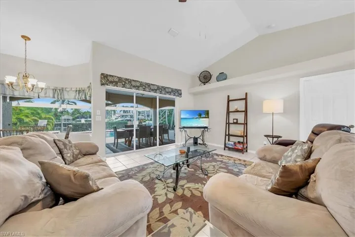 Living area featuring tile patterned floors, a sunroom, a chandelier, and high vaulted ceiling