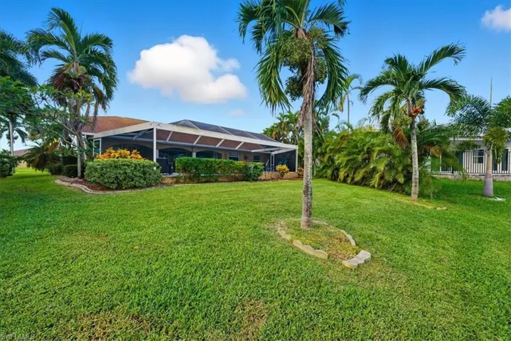 View of grassy yard featuring glass enclosure and a sunroom