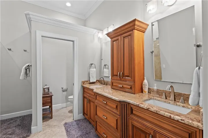 Bathroom with double vanity, ornamental molding, and light tile patterned floors