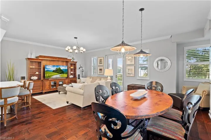 Dining area with dark wood finished floors, healthy amount of natural light, a chandelier, and ornamental molding