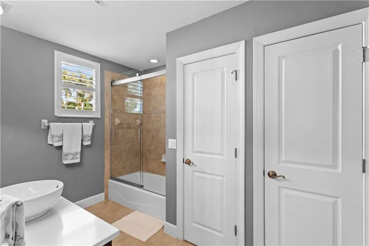 Full bath featuring vanity, bath / shower combo with glass door, light tile patterned flooring, and recessed lighting