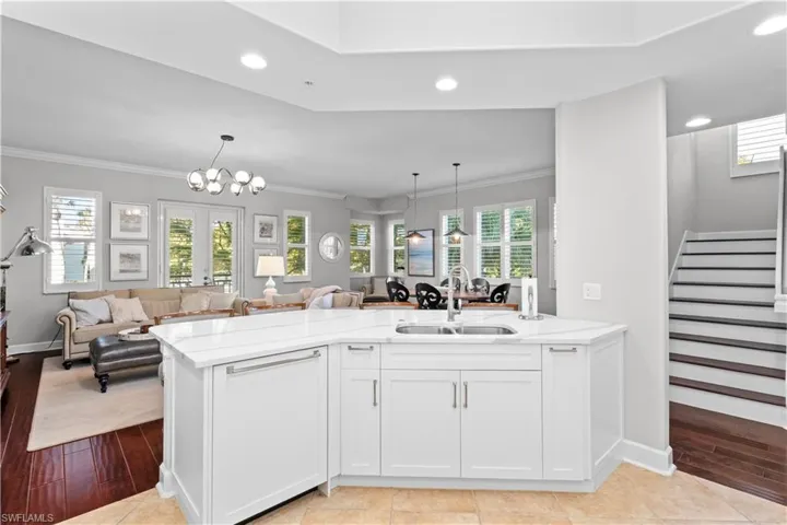 Kitchen featuring white cabinetry, a peninsula, open floor plan, pendant lighting, and light stone countertops