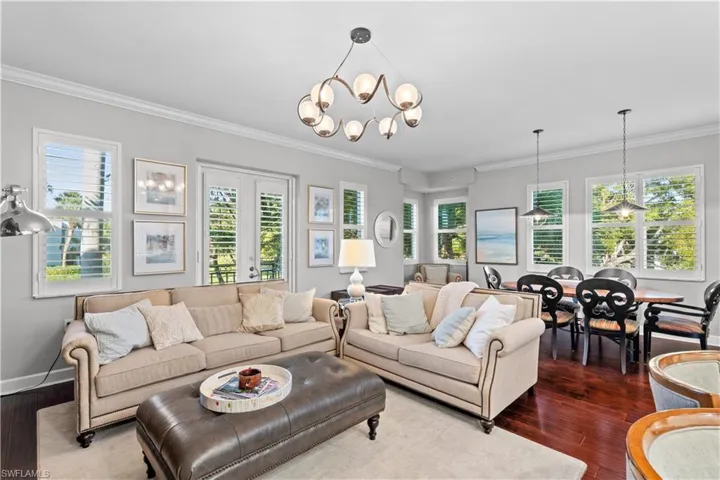 Living room featuring a chandelier, healthy amount of natural light, dark wood-style floors, and ornamental molding