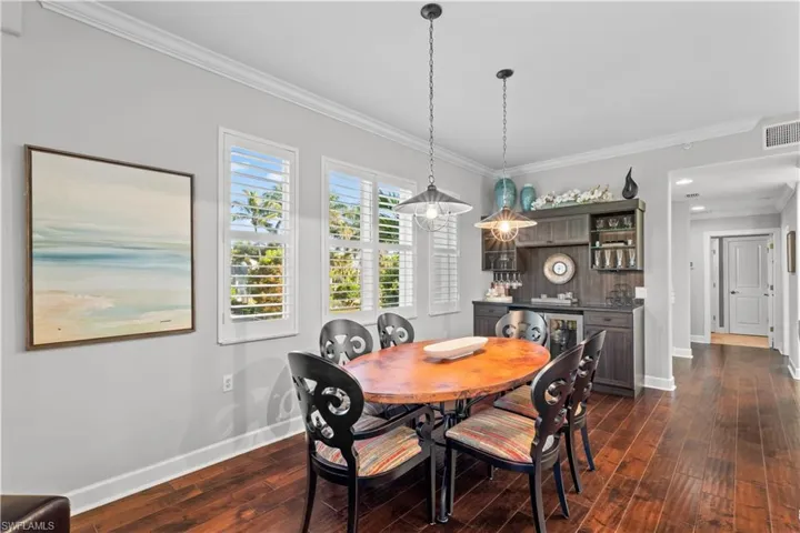 Dining space featuring crown molding and dark wood-type flooring