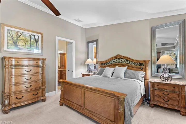 Bedroom featuring light carpet, ornamental molding, connected bathroom, and a ceiling fan