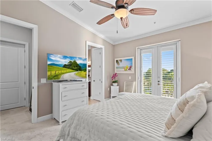 Bedroom featuring crown molding, light colored carpet, ensuite bath, access to exterior, and a ceiling fan