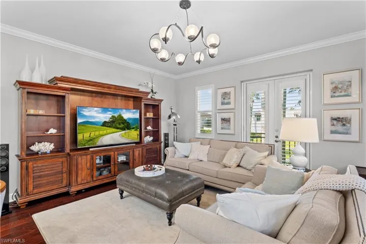 Living room featuring crown molding, dark wood-style floors, and a chandelier