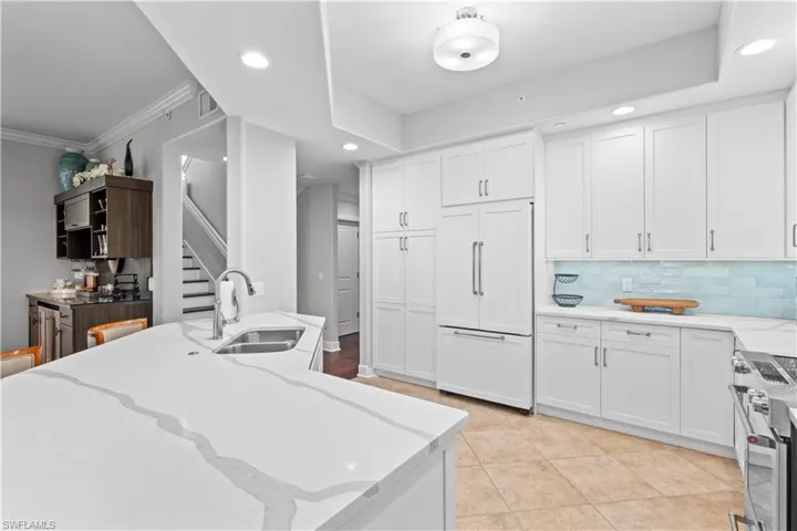Kitchen featuring light stone counters, paneled refrigerator, white cabinetry, stainless steel electric range oven, and recessed lighting