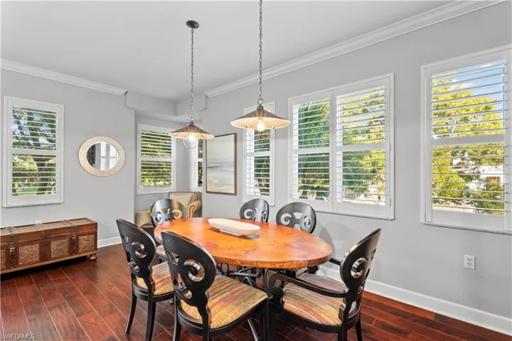 Dining space with crown molding, dark wood finished floors, and healthy amount of natural light