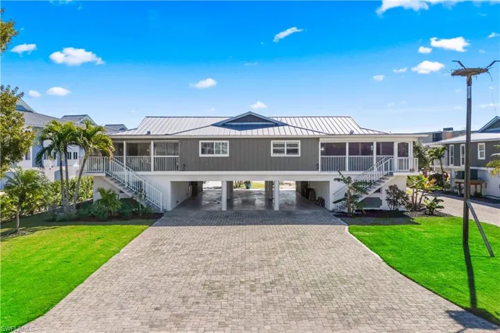 Beach home featuring stairs, a carport, a front yard, and a metal roof