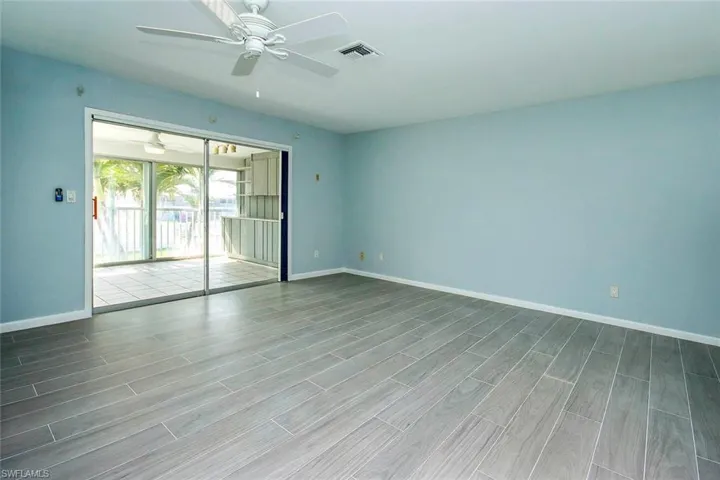 Unfurnished room with wood tiled floor, visible vents, ceiling fan, and baseboards