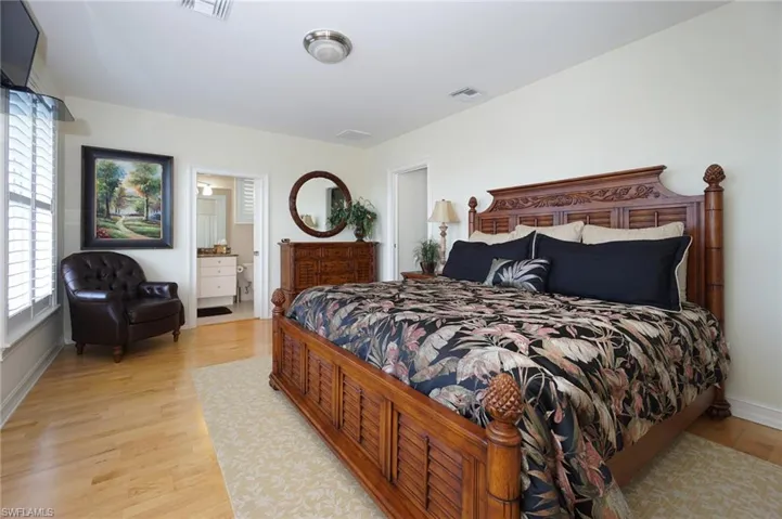 Bedroom featuring light wood-style floors, visible vents, connected bathroom, and baseboards