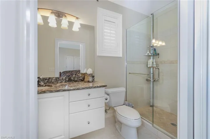 Full bathroom featuring toilet, tile patterned flooring, a shower stall, and vanity