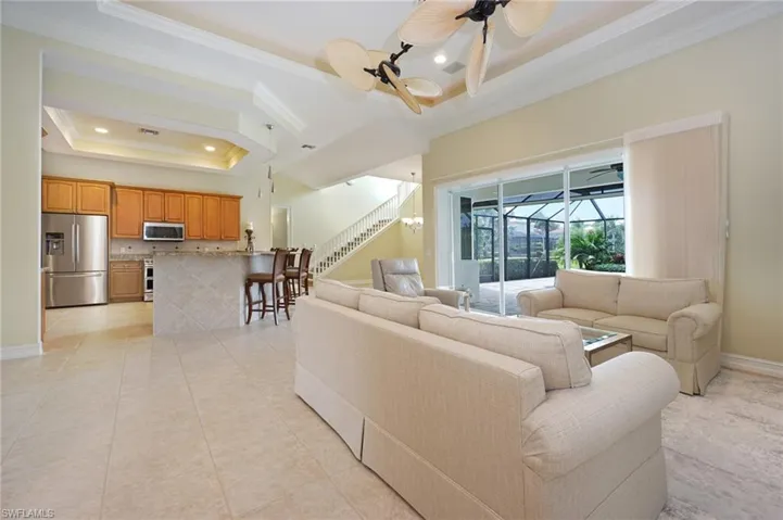 Living room featuring a tray ceiling, ornamental molding, a sunroom, ceiling fan, and recessed lighting