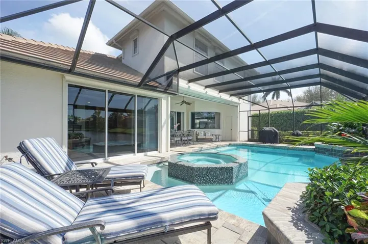 View of swimming pool featuring a lanai, a grill, a pool with connected hot tub, a ceiling fan, and a patio area