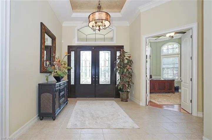 Foyer entrance featuring ornamental molding, a tray ceiling, french doors, and light tile patterned floors