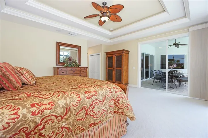 Bedroom with light carpet, a tray ceiling, ornamental molding, and visible vents