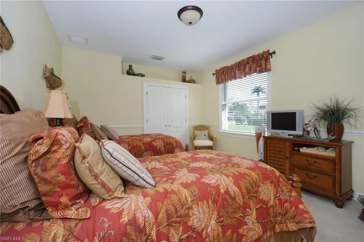 Bedroom with a closet, light carpet, and visible vents