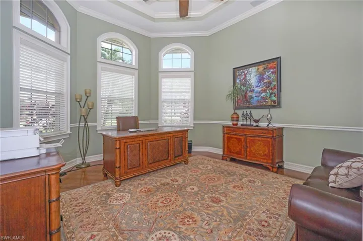 Office area with a towering ceiling, baseboards, and crown molding