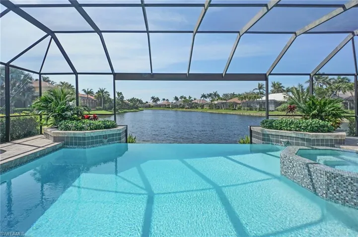 View of pool with a pool with connected hot tub, glass enclosure, and a water view