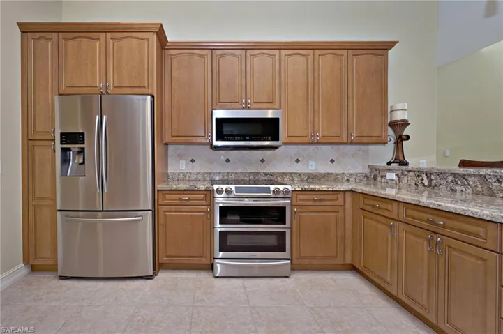 Kitchen with appliances with stainless steel finishes, decorative backsplash, and light stone countertops
