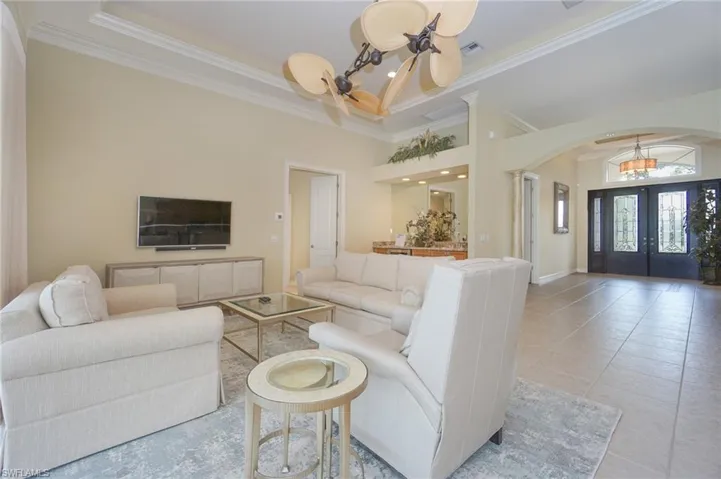 Living area with arched walkways, french doors, tile patterned floors, a chandelier, and a towering ceiling