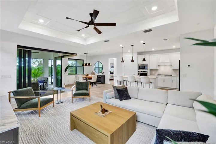 Living area with detailed tray ceiling, fan, recessed lighting and light tile flooring