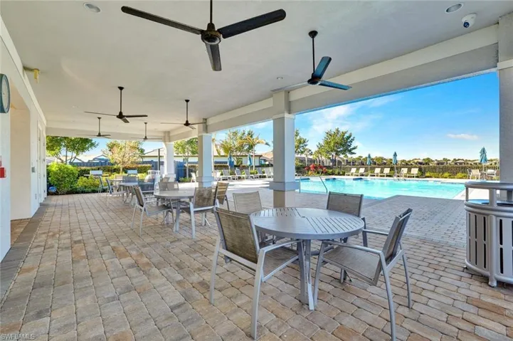 View of patio featuring outdoor dining space, grilling space, a community pool and ceiling fans