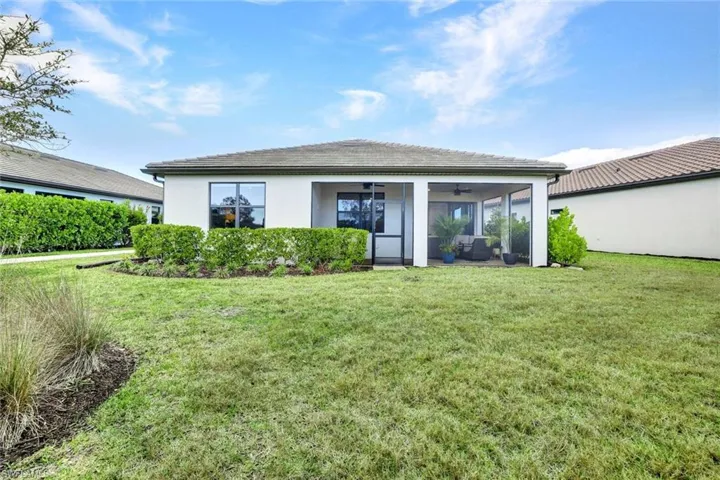 Rear view of property with a yard, stucco finish, and a lanai