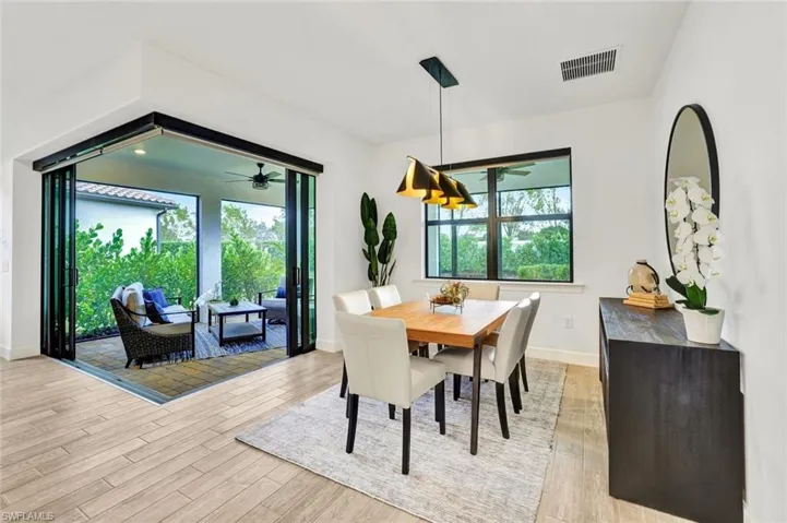 Dining area with light tile floors, decorative light fixtures, and a view of the lanai with zero-corner sliding doors