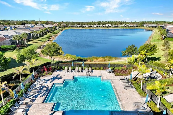 Aerial view of community pool featuring a patio, a water view, and a residential view
