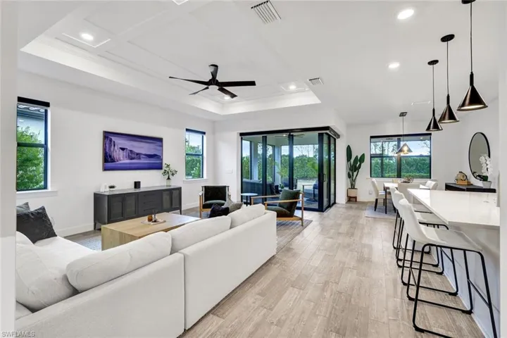Living room with recessed lighting, a ceiling fan, light tile floors, and a detailed tray ceiling