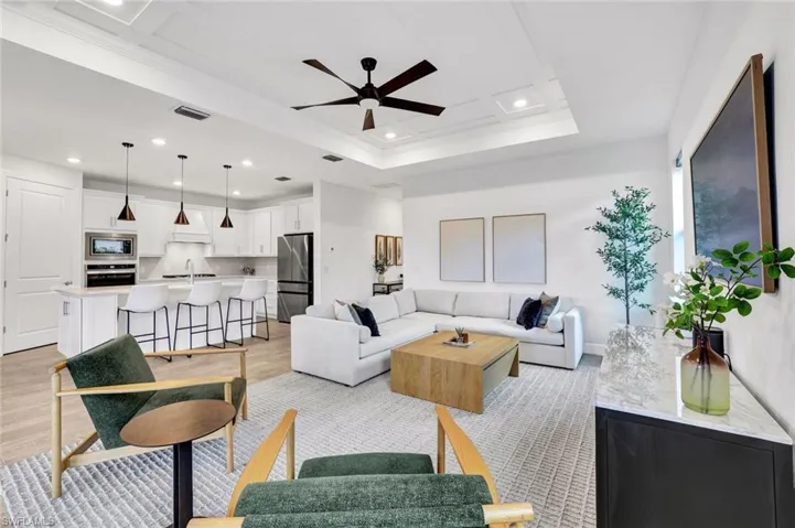 Living room featuring ceiling fan, light tile finished floors, recessed lighting, and detailed tray ceiling