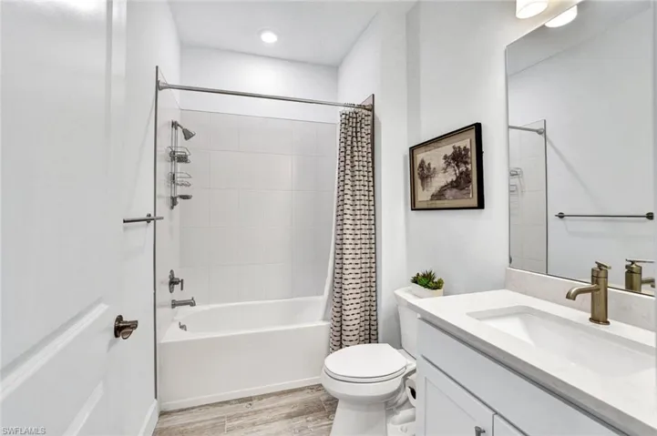 Full bathroom featuring shower / bathtub combination, vanity with quartz countertops and square sink, and light tile flooring