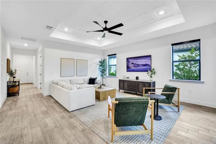 Living area featuring recessed lighting, a ceiling fan, light tile flooring, and a detailed tray ceiling
