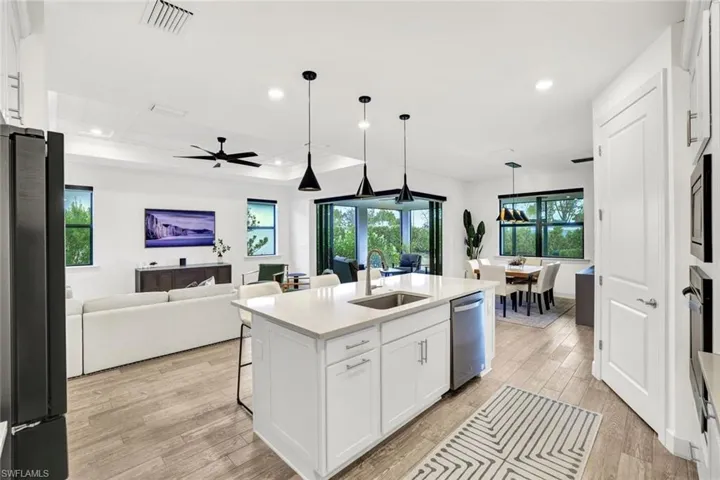 Kitchen featuring white cabinetry, light tile flooring, stainless steel appliances, and decorative light fixtures