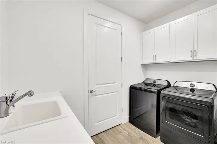 Laundry room with new washer and dryer, light tile flooring, and counter and cabinet space