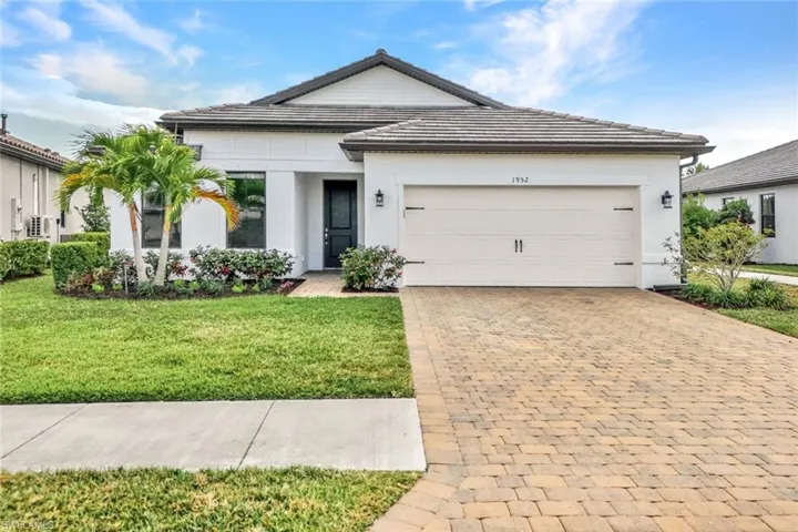 View of front of property with driveway, a front lawn, an attached garage, stucco siding, and a tile roof