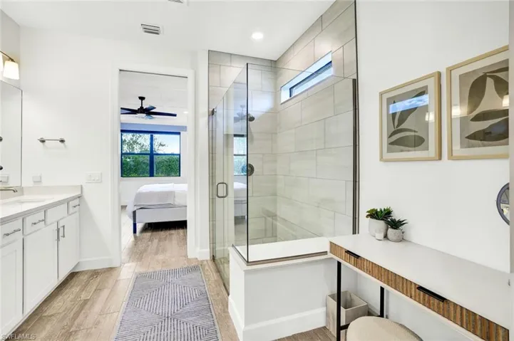 Master ensuite Bathroom featuring vanity, a frameless glass shower with tile to the ceiling, and light tile finished floors