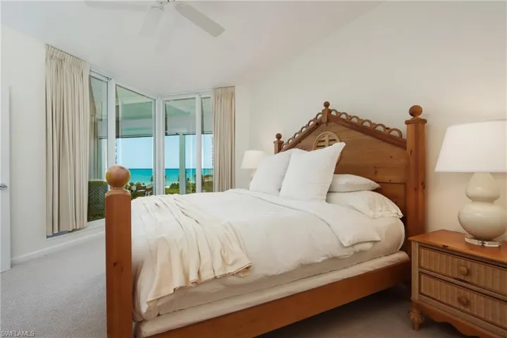 Carpeted bedroom featuring ceiling fan, a water view, and access to exterior